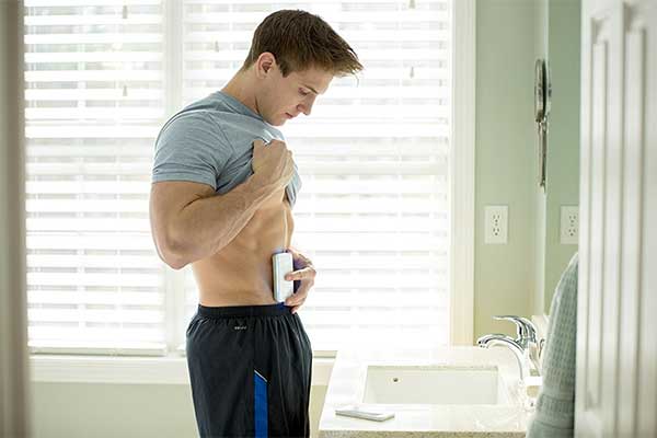 Man using a body fat scanner on his abs